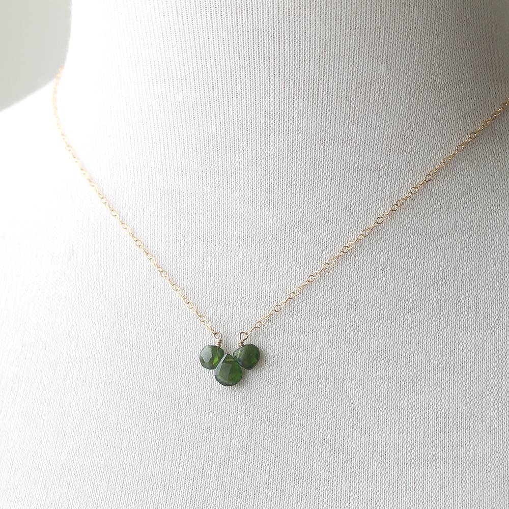 Necklace with green gemstones on a mannequin bust against a white background