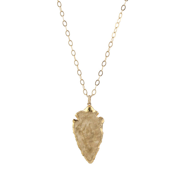 A gold-colored carved arrowhead pendant on a gold-filled chain.