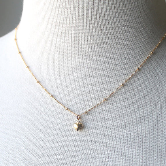 Gold necklace with a heart pendant on a mannequin bust.