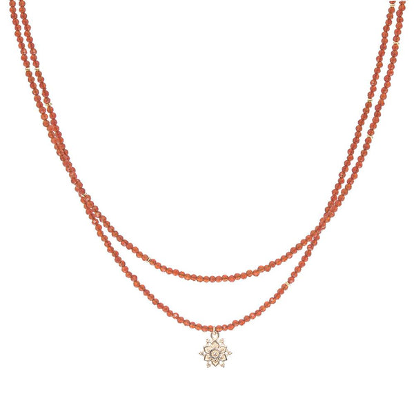 Two layered necklaces with carnelian  beads and a gold flower pendant on a white background