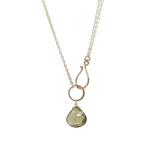 Gold necklace with a green teardrop pendant on a white background