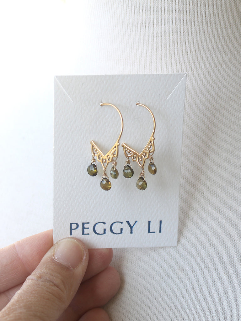 Gold earrings with green beads on a Peggy Li card