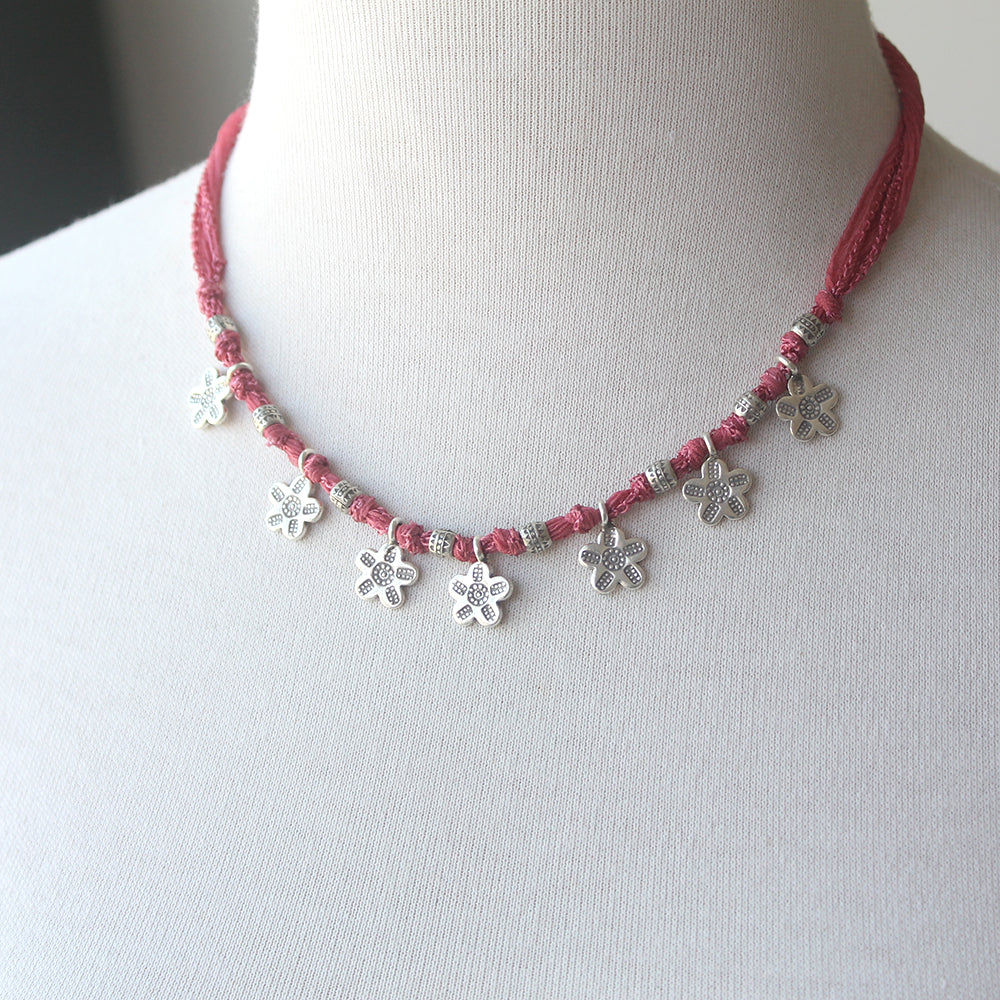 Necklace with pink cord and silver flower charms 