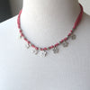 Necklace with pink cord and silver flower charms 
