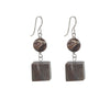 Pair of earrings with brown spherical beads and square wooden pendants on a white background