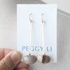 Pair of earrings with beige stones on a Peggy Li branded card.