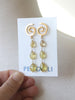 Gold earrings with yellow teardrop-shaped stones on a Peggy Li card.