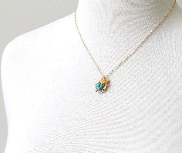 Gold bird charm and nest with turquoise eggs necklace